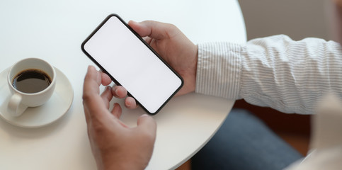 Obraz premium Businessman holding blank screen smartphone in comfortable workspace