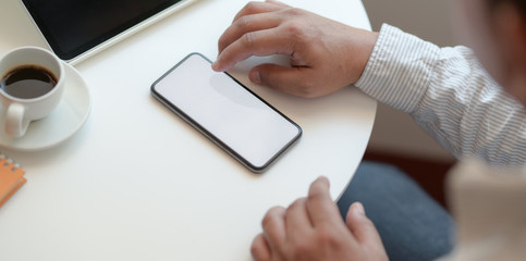Young professional businessman looking for information on blank screen smartphone