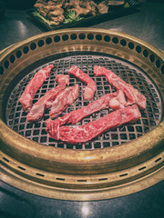 Japanese BBQ restaurant barbecue grill top view of table grilling yakiniku of raw steak meat premium cuts. Japan culture dining experience cooking.