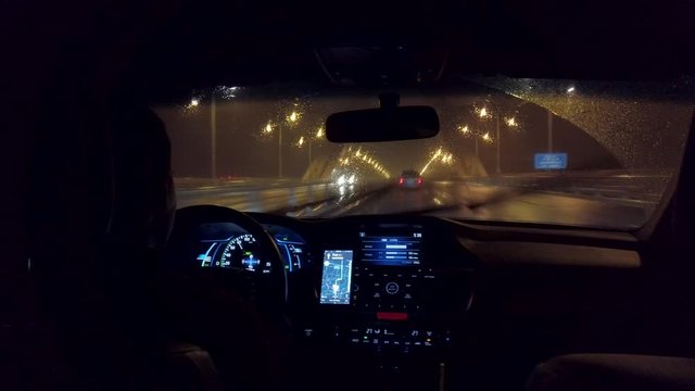 Chinese uber drives down highway in the rain at night. Rainy highway with professional driver in ride share service using app for navigation. Ride hailing service in China in the evening.