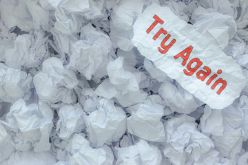 The word  TRY AGAIN  is placed on the background paper in the big trash.