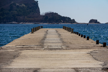 Fototapeta na wymiar Pier on Beach Greco, Budva, Montenegro leading to Saint Nikola Island