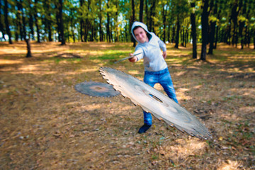 The guy throws a circular knife to attack the enemy in the forest, discs from a circular saw fly...