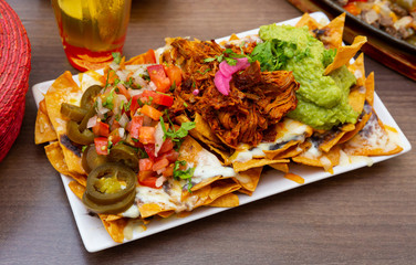 Corn chips nachos with homemade guacamole sauce, meat, cheese