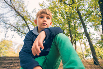 A boy sits on the steps in an old abandoned park, view from below.