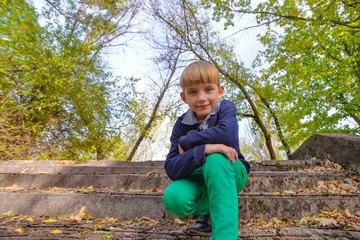 A boy sits on the steps in an old abandoned park, view from below.