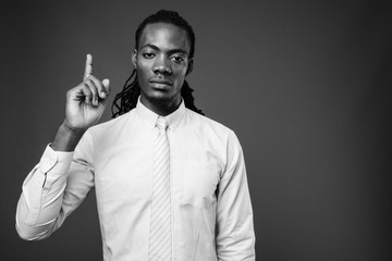 Young handsome African businessman against brown background