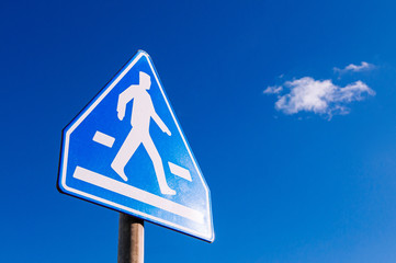 Crosswalk pedestrian crossing sign against blue sky