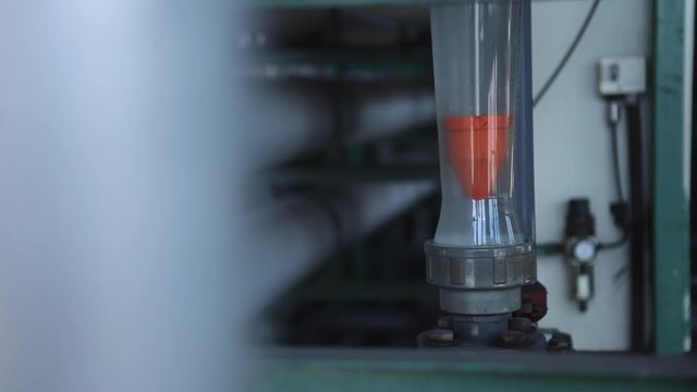 Panning shot reveals a glass tube on a huge machine indicating the heat level of the process in palm oil factory. Located in Malaysia (Kilang Kelapa Sawit)