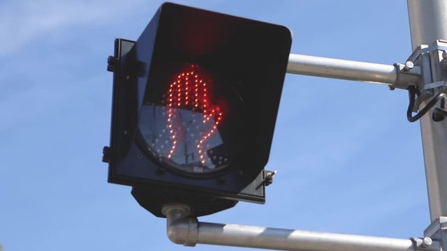 rack focus shot of a crosswalk sign with a red hand.