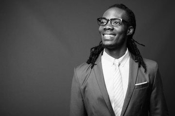 Young handsome African businessman wearing eyeglasses against brown background