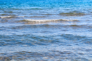 Clear water texture in blue and orange. Background of the ocean and the sea backlit by the sun. Soft waves. Natural water
