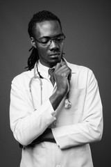 Young handsome African man doctor against brown background