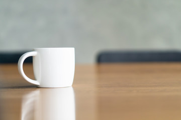 White ceramic coffee mug on the table in coffee bar with copy space.  Coffee mug background.