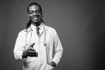 Young handsome African man doctor against brown background