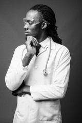 Young handsome African man doctor wearing protective glasses against brown background