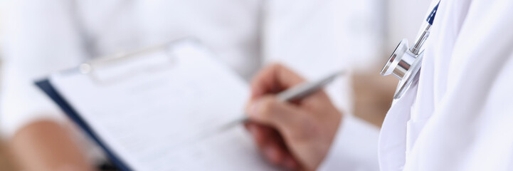 Male doctor hand hold silver pen and showing pad. Physical agreement form signature disease prevention ward round reception consent contract sign prescribe remedy healthy lifestyle concept