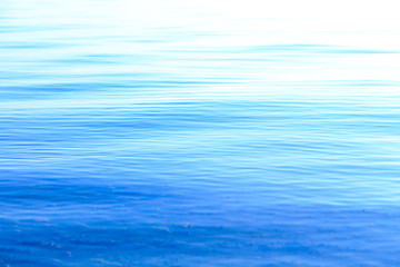 Clear water texture in blue and orange. Background of the ocean and the sea backlit by the sun. Soft waves. Natural water