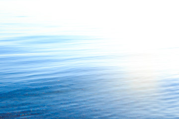 Naklejka premium Clear water texture in blue and orange. Background of the ocean and the sea backlit by the sun. Soft waves. Natural water