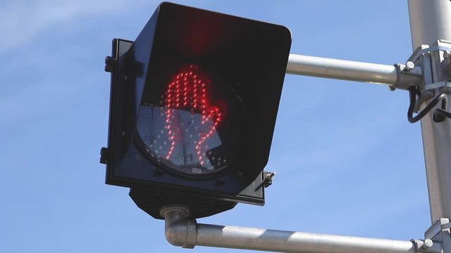 crosswalk sign changing from led person to led flashing red stop hand sign.