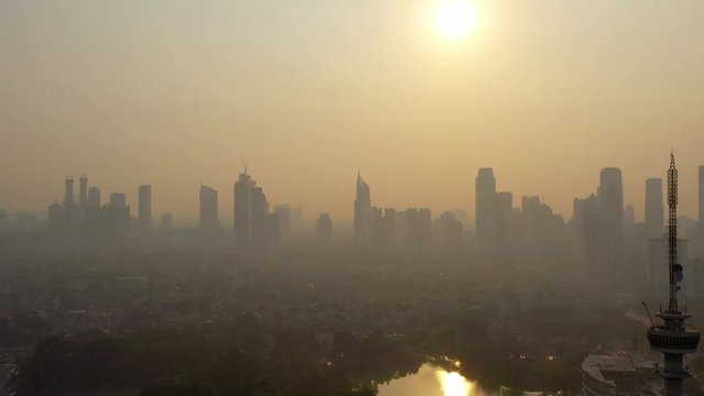 Aerial view of Extreme air pollution of Jakarta City with TVRI Tower in foreground and city skyline background. Dolly Motion