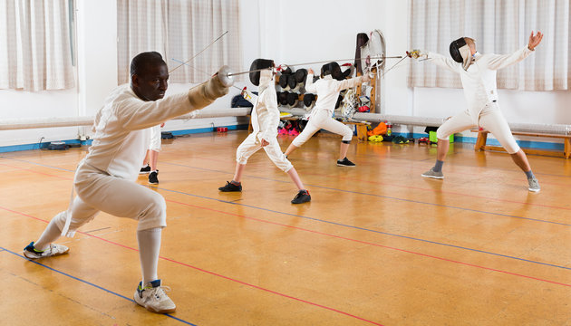 African American wearing fencing uniform practicing with foil - Powered by Adobe