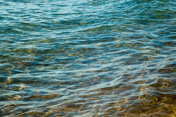 Clear water texture in blue and orange. Background of the ocean and the sea backlit by the sun. Soft waves. Natural water