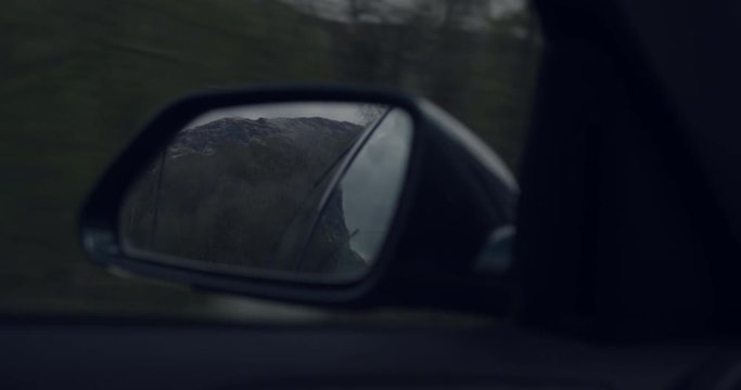 4K Tourists Rear View Mirror in a car in The Glen Coe Scottish Mountains. Reflection of Trees and sky in Natural Rural Scotland.