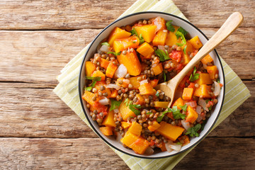 Low-calorie hot stew of pumpkin, lentils, onions and carrots close-up in a bowl. Horizontal top view
