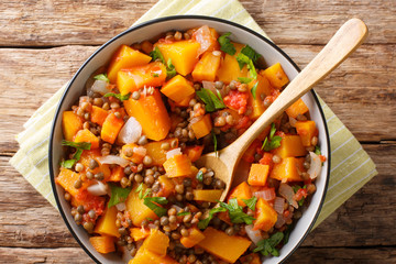 Dietary ragout with pumpkin, lentils, onion and carrot in a bowl close-up. Horizontal top view