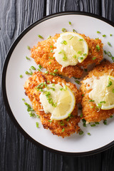 Tasty lemon romano chicken cutlet breaded close-up on a plate. Vertical top view