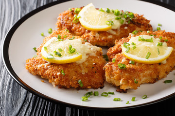 Romano cheese chicken cutlet fried breaded served with lemon and green onion closeup on a plate. horizontal