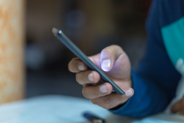 A man holding the hands of a mobile phone, is looking for online work on the Internet or social connection with the application for digital devices with 5G technology in an internal coffee shop.