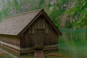 A boathouse on a blue mountain lake with high mountains in the background