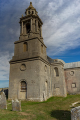 Fototapeta na wymiar An old church in a cemetery in the sunshine and blue sky