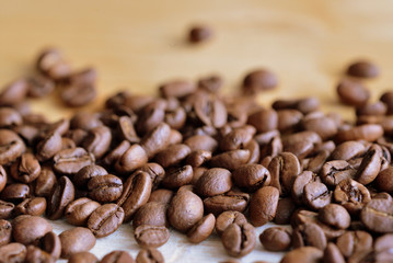 Roasted coffee beans scattered on a wooden surface close up
