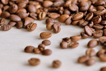Roasted coffee beans scattered on a wooden surface close up
