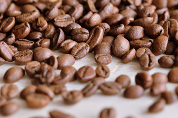 Roasted coffee beans scattered on a wooden surface close up