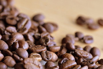 Roasted coffee beans scattered on a wooden surface close up