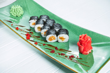 Close up view on maki sushi roll with mussel on green plate isolated on white wooden background. japanese sushi food. Seafood