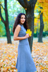 woman posing with autumn leaves in city park, outdoor portrait
