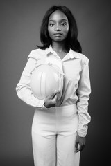 Young beautiful African Zulu businesswoman with hardhat against brown background