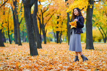 woman posing with autumn leaves in city park, outdoor portrait
