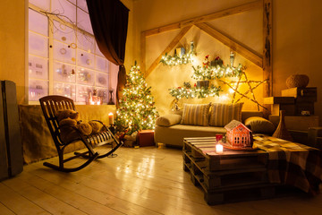 Christmas eve in the living room.. Homemade gingerbread house on background room decorated for Christmas.
