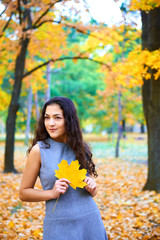 woman posing with autumn leaves in city park, outdoor portrait