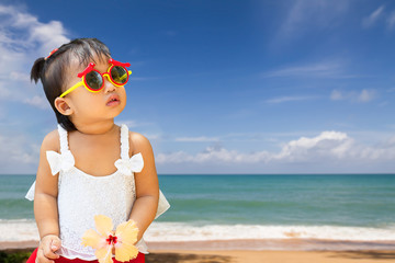 Little cute toddler baby girl wearing sun glasses on blurred beach background