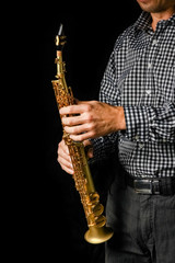 Naklejka premium soprano saxophone in hands on a black background
