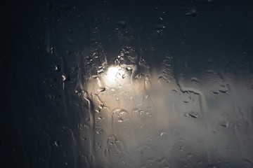 Abstract of water drops on glass window, dark tone, selective focus..