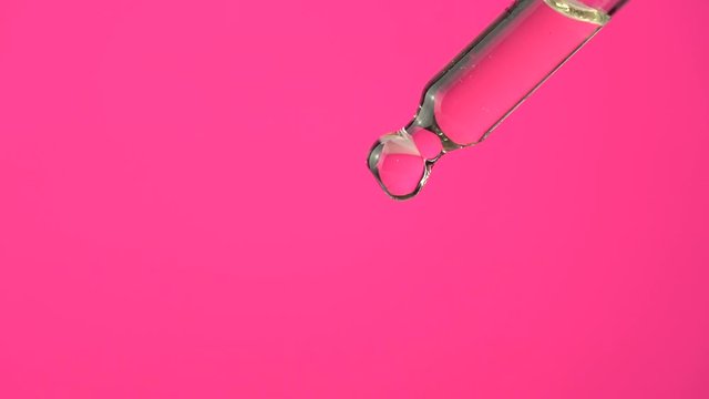 Extreme macro close up of droplet pipette dosing biological and ecological oil of the hemp plant.  Pharmaceutical herbal cbd oil, organic pharma concept, on pink background.