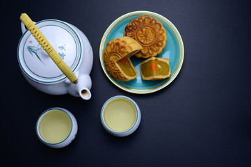 Mid-Autumn Festival moon cake dish with hot tea pot and cups o black table